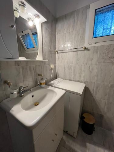 a white bathroom with a sink and a mirror at Eva's house in Rafina