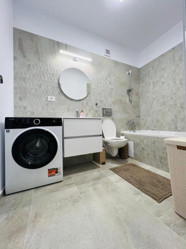 a washing machine in a bathroom with a toilet and a tub at Richy North in Voluntari