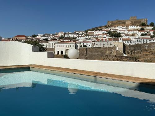 a swimming pool with a city in the background at Casa Amarela_ Alojamento Local in Mértola