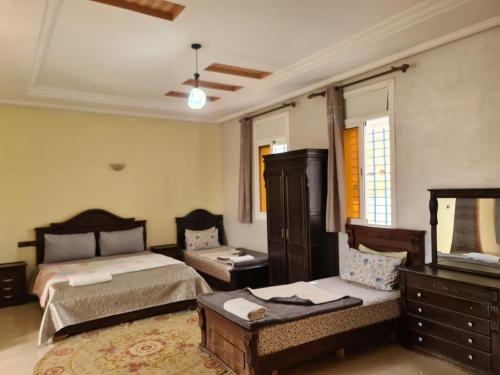 Un dormitorio con dos camas y un televisor de pantalla plana. en blue door imsouane, en Imsouane