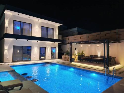 een zwembad voor een huis 's nachts bij شاليه فيلا تاج in Al Rama
