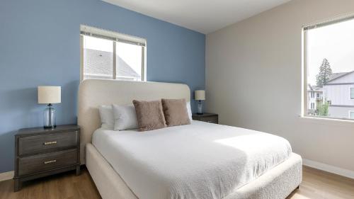 a bedroom with a white bed and two windows at Landing Apartments - Woodburn in Woodburn
