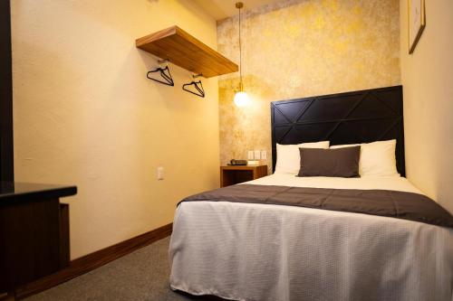 a bedroom with a large bed with a black headboard at Hotel Boutique Lumiere in Tampico