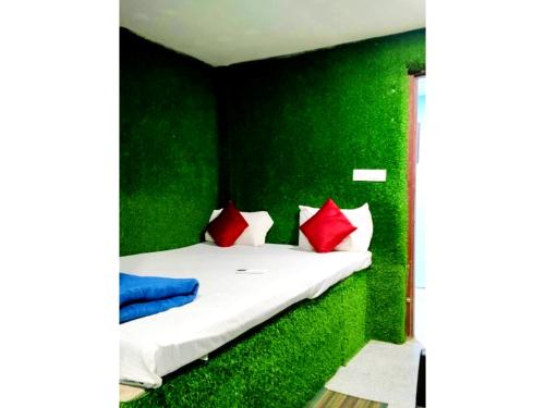 a green walled bedroom with a bed with red pillows at Hotel Shree Krishna Nearby Bhubaneswar Railway Station in Bhubaneshwar