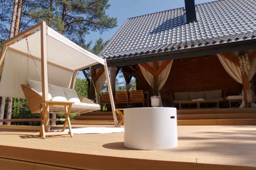 a porch with a hammock and a chair and a house at Forest Home Dębowa 18 in Łuka