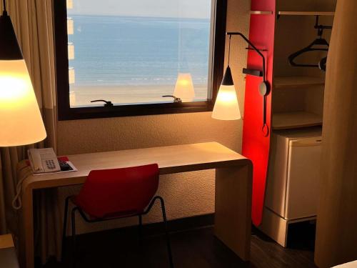a room with a desk with a red chair and a window at ibis Santos Gonzaga Praia in Santos