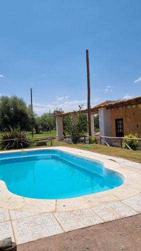 a blue swimming pool with a house in the background at Finca la margarita in Tinogasta