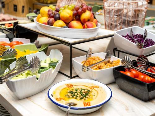 Un buffet con tazones de comida en una mesa. en Novotel Bucharest City Centre, en Bucarest