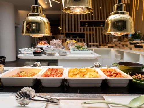 a buffet with several trays of food on a counter at Novotel Bucharest City Centre in Bucharest