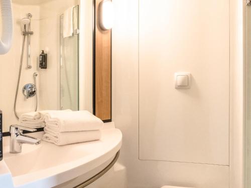 a bathroom with a sink and a shower with towels at Ibis Albi in Albi