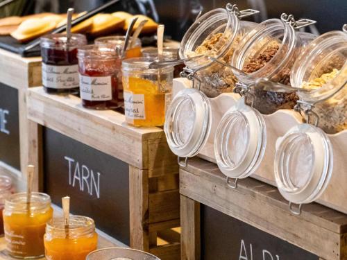 Un buffet con tarros de miel y otros alimentos. en Ibis Albi, en Albi