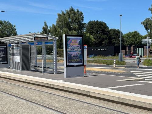 a bus stop with a sign in front of it at Mercure Caen Cote De Nacre in Caen