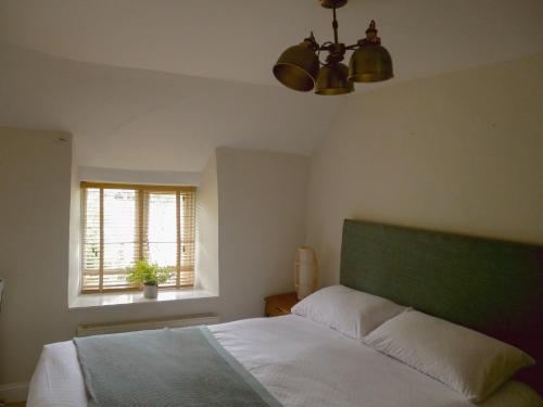 Schlafzimmer mit einem Bett mit einem grünen Kopfteil und einem Fenster in der Unterkunft Charlotte's Cottage, a Charming Cotswolds Getaway in Adlestrop