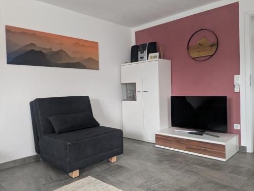 a living room with a chair and a flat screen tv at Allgäu-Genuss in Halblech