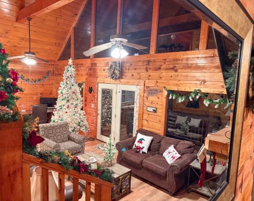 a living room with a christmas tree and a couch at Charming Cabin, Seasonal Decor & Pool, 3min to Pkwy, Grill, GameRoom, Wifi & Workstation, Sleeps 14 in Pigeon Forge