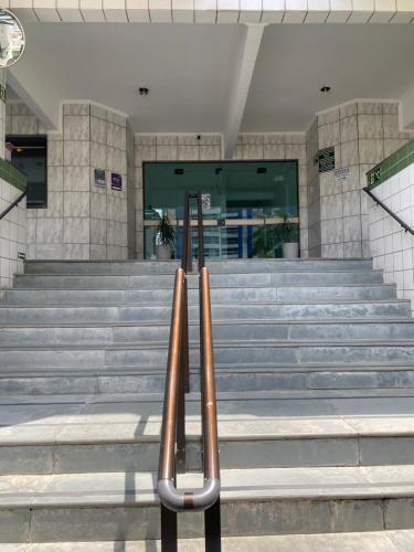 Un par de bancos de metal frente a un edificio. en Apto até 6 pessoas -PG Aviação - 150mts e 1 vaga, en Praia Grande