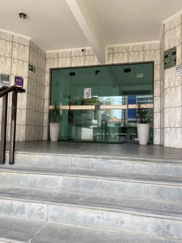 una tienda frente con dos macetas en las escaleras en Apto até 6 pessoas -PG Aviação - 150mts e 1 vaga, en Praia Grande