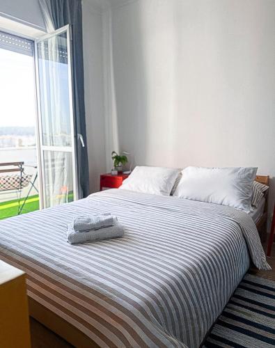 a bedroom with a bed with a striped blanket and a window at Apartamento com terraço em Lisboa in Amadora
