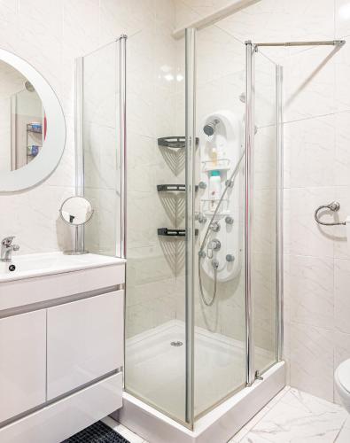 a white bathroom with a shower and a sink at Apartamento com terraço em Lisboa in Amadora