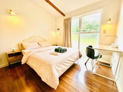 Un dormitorio con una cama y un escritorio y una ventana. en Beautiful villa by the sea, en Auckland
