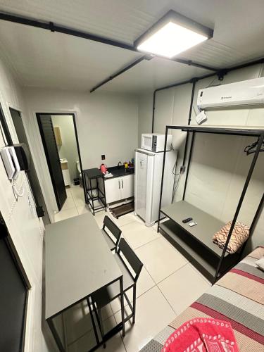 a room with a table and chairs and a kitchen at Loft c/ Ar no Centro (2 camas) in Jaú