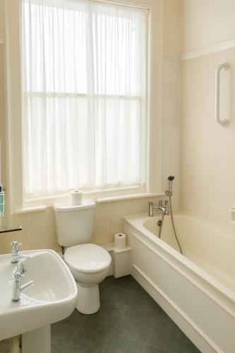 a bathroom with a toilet and a tub and a sink at Albany, Brighton & Hove in Brighton & Hove