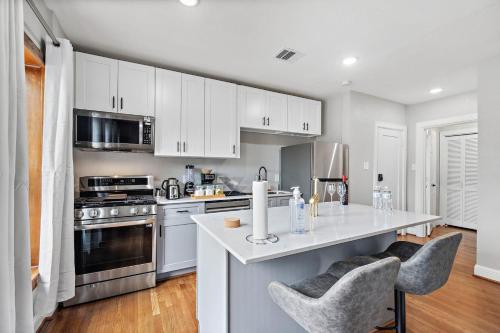 a kitchen with white cabinets and a counter with chairs at Homey Apt Nr Med Center Fire Pit Bbq Wifi Games in Houston