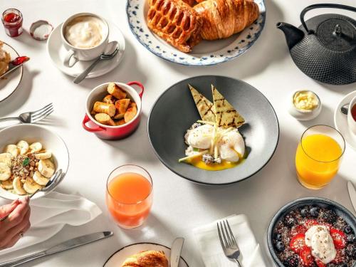 a table with plates of breakfast foods and drinks at Sofitel London Heathrow in Hillingdon