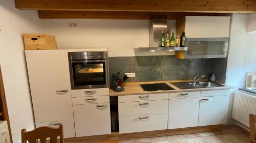 una cucina con mobili bianchi e un forno a piano cottura di Ferienhaus "Spatzennest" Eifel Gerolstein Hunde ok a Oberbettingen