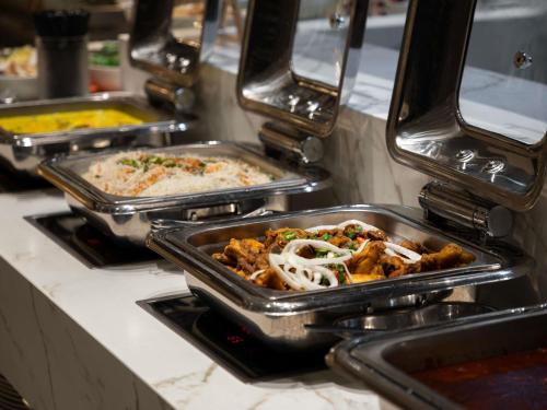 a row of trays of food on a counter at Novotel Kuala Lumpur City Centre in Kuala Lumpur