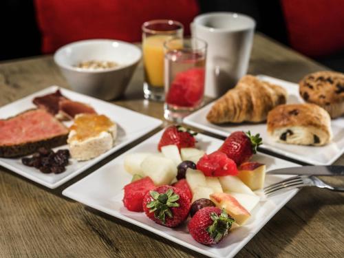 3 platos de comida en una mesa con fruta y repostería en Ibis Barcelona Santa Coloma, en Santa Coloma
