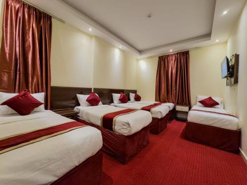 a hotel room with three beds with red pillows at فندق صفوة المشاعر in Al Khansāk