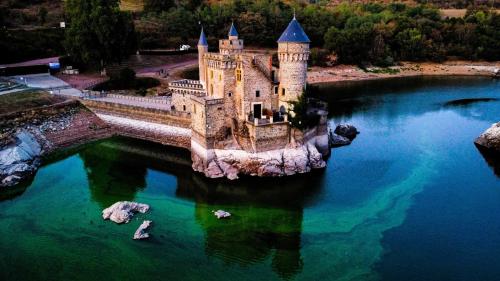 a castle in the middle of a body of water at Chambre d'hôtes Les Myriades D'Or in Regny