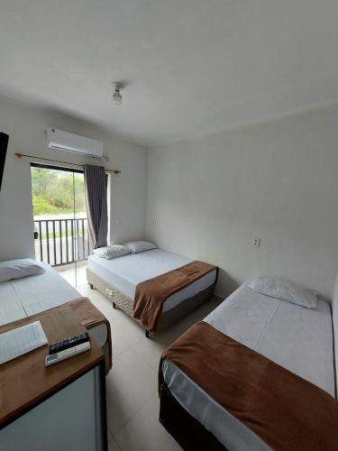 a hotel room with two beds and a balcony at Pousada das Flores in Aparecida