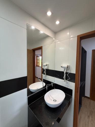 a bathroom with two sinks and a mirror at Suítes Refúgio in Abraão