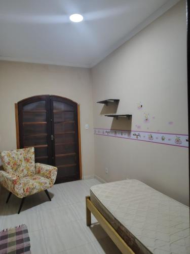 a bedroom with a bed and a chair at Casa amarela com fundos para seminário in Aparecida