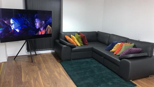 a living room with a couch with a flat screen tv at Posh 1 Bed Property Close to Lakeside Shopping Centre- Direct Links to London in West Thurrock