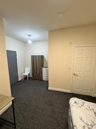 a room with a bed and a door and a chair at Barnsley Guesthouse Couple Room Ground Floor in Barnsley