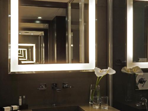 a bathroom with a sink with a mirror and a flower at Novotel Buenos Aires in Buenos Aires