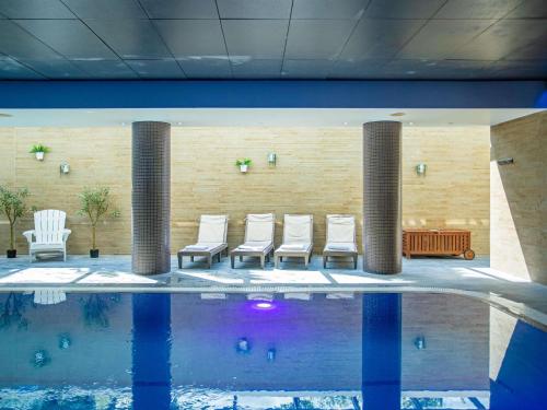 a group of chairs sitting next to a swimming pool at Novotel Edinburgh Park in Edinburgh