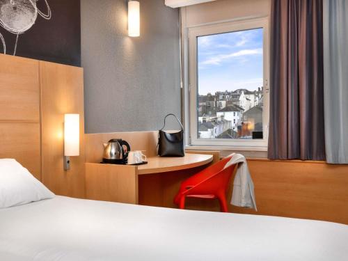 a hotel room with a bed and a desk and a window at ibis Brighton City Centre - Station in Brighton & Hove