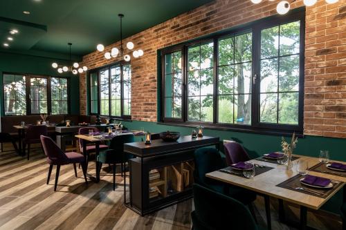 Un comedor con mesas y sillas y ventanas. en Queens cottage, en Shumen