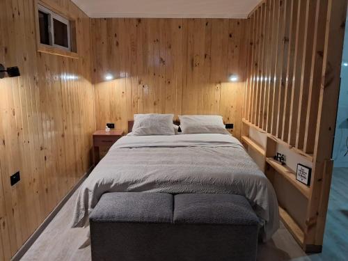 a bedroom with a large bed with wooden walls at Tiny House Ruta 215 in Osorno