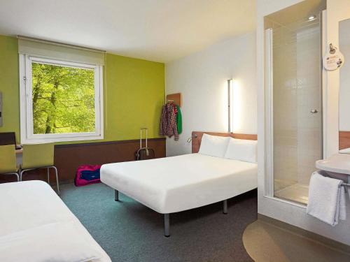 a hotel room with two beds and a window at ibis budget Wrocław Stadion in Wrocław