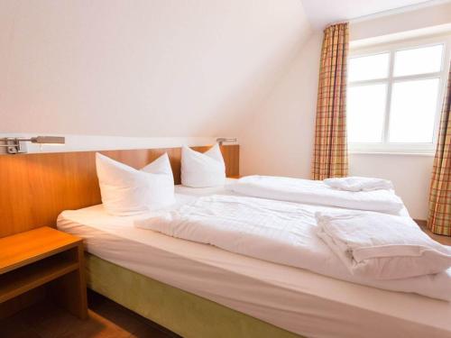 una camera da letto con un grande letto bianco con una finestra di Manslagt - Greetsiel a Greetsiel