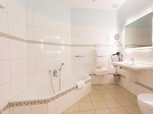 een witte badkamer met een bad en een wastafel bij Twixlum - Greetsiel in Greetsiel