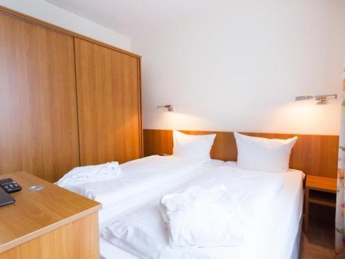 een slaapkamer met een bed met witte lakens en een bureau bij Twixlum - Greetsiel in Greetsiel