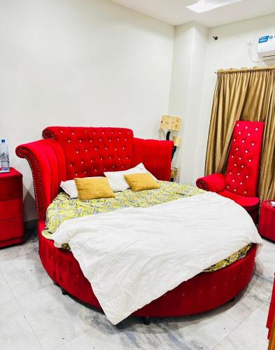 a red bed in a room with two red chairs at Flat in wah cantt in Wāh