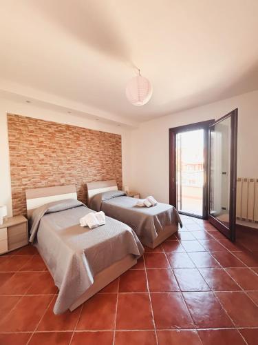 two beds in a room with a brick wall at Dimora Lucci Marini in Taranto