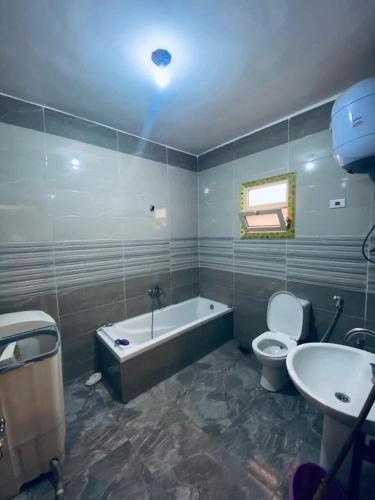 a bathroom with a tub and a toilet and a sink at Vrtn hotel in Amman